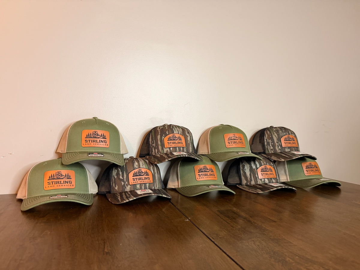 Pyramid display of green and camouflage custom leather patch hats created by Stay Anchored for Stirling Land Services